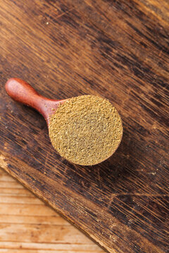 Ground Cumin Spice Powder in Wooden Spoon on Rustic Wood Background