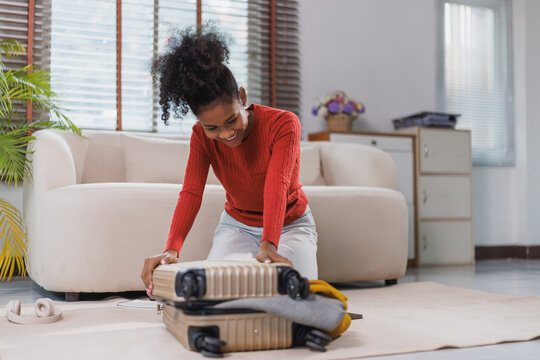 Happy black woman packing suitcase for travel