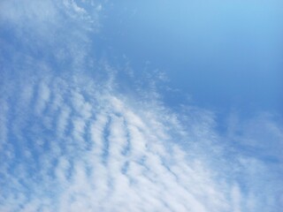 Soft white clouds drift across a vast, clear blue sky and Open Space for Background and Copy © agust_kha