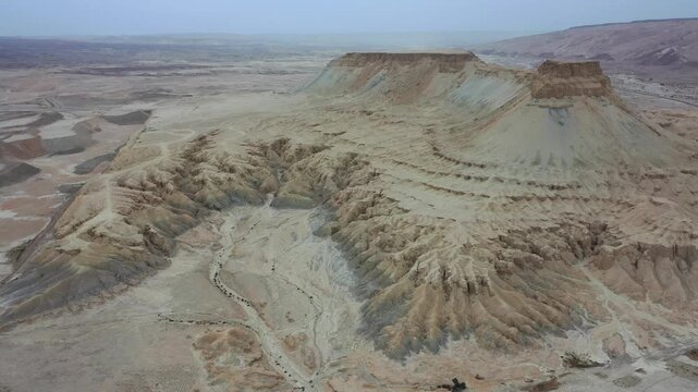 Aerial view of Mount Zin in the Negev desert with rugged limestone cliffs, dry wadis, and vast arid landscape under a clear sky in Yeruham, South District, Israel.