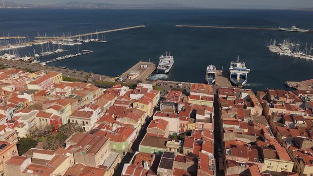 Ferry Along The Waterfront Of Carloforte On San Pietro Island, Sardinia, Italy, With The Harbor And Coastal Town. Aerial Drone Shot