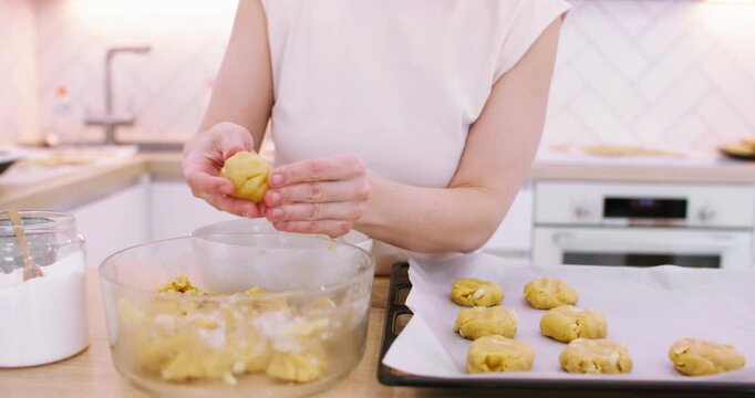 Pastry preparation. Baking cookies. Chef female hand forming dough shortbread pieces with peanut on parchment paper tray at kitchen.