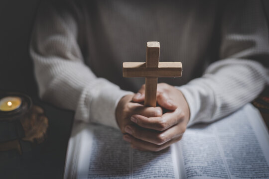 A woman kneeling in prayer with a cross in a room, symbolizing Christian faith, worship, hope, spiritual guidance, and peace.