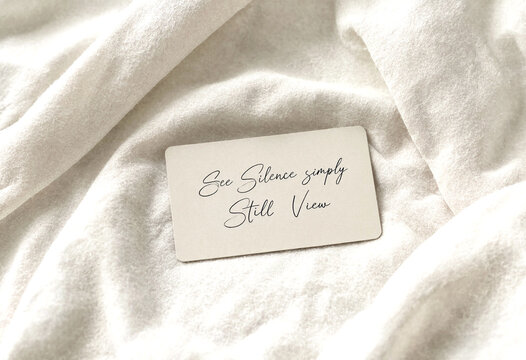 Small inspirational card with handwritten text on a soft white fabric background for motivation