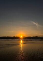 Obraz premium Golden Sunset Over Tropical Beach with Sunlight Reflection on Wet Sand