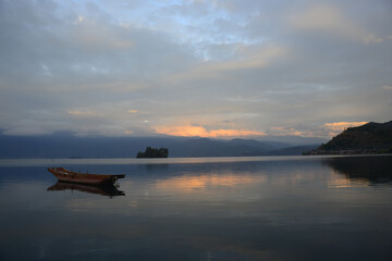 Wooden Boat on Quiet Lake at Sunset with Mountain Views © CaoVan