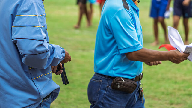 Referee checking starting pistol revolver for sports competition. 
Sports official holding revolver starting pistol, checking cylinder and blank ammunition before initiating a race. Selective focus.