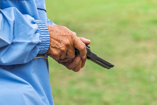 Referee checking starting pistol revolver for sports competition. 
Sports official holding revolver starting pistol, checking cylinder and blank ammunition before initiating a race. Selective focus.