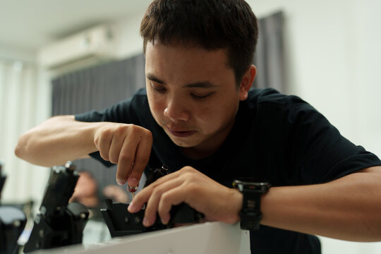 The focus is on the hands of a technician setting up a 3D printer to print a clear white plastic model, using cutting-edge technology and concentrating on specific points within the laboratory.