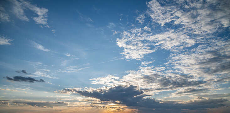 Wide Blue Evening Sky with Scattered Altocumulus Clouds and Warm Horizon.
