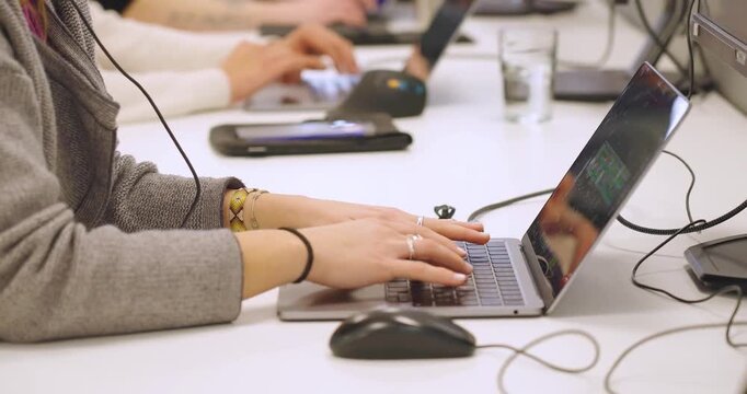 Students typing on laptop computers in classroom setting during professional training course.