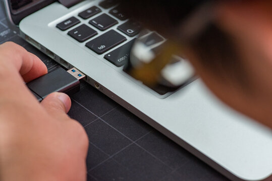 close-up image shows the use of a USB flash drive to connect to a laptop.
Hand inserting Flash drive memory drive plugged into a computer laptop port.