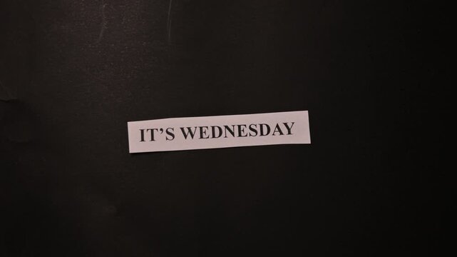 It's Wednesday Text on Tiny Paper Placed on Black Book Background