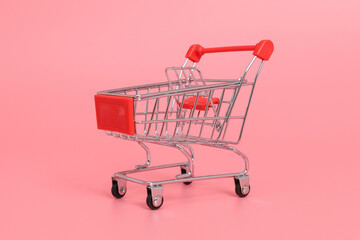 Mini shopping cart with red handle on pink background © PhamHong