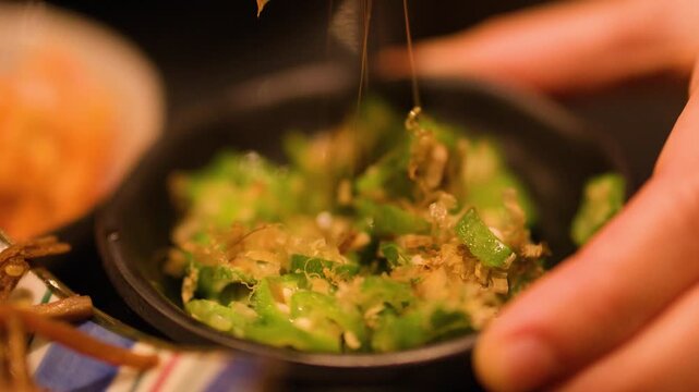 Close Up of Person Eating Okra Salad with Chopsticks