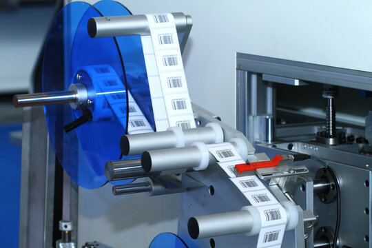 Automatic barcode label roll on industrial labeling machine in factory