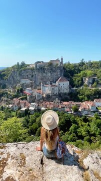 woman sitting on cliff admiring rocamadour medieval village view in lot france. Rocamadour