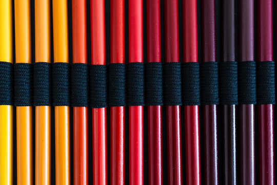 close-up of yellow orange and red colored pencils neatly lined up in pencil case, concept of creativity, drawing, education and art supplies