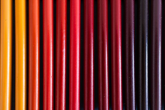 close-up of yellow orange and red colored pencils neatly lined up in pencil case, concept of creativity, drawing, education and art supplies