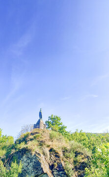 Esch-sur-Sure, Wiltz, Grand-Duche de Luxembourg, September 07, 2025, Towering church spire ascends behind scenic hillside with winding trail