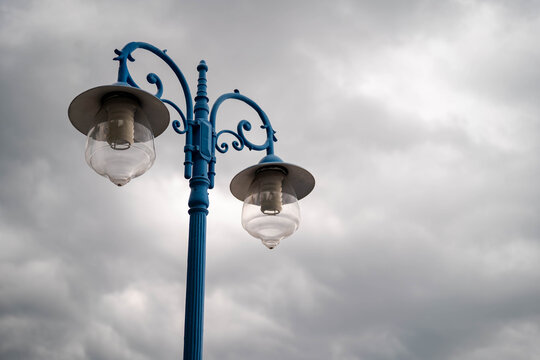 Elegant blue street lamp against a moody, cloudy sky.