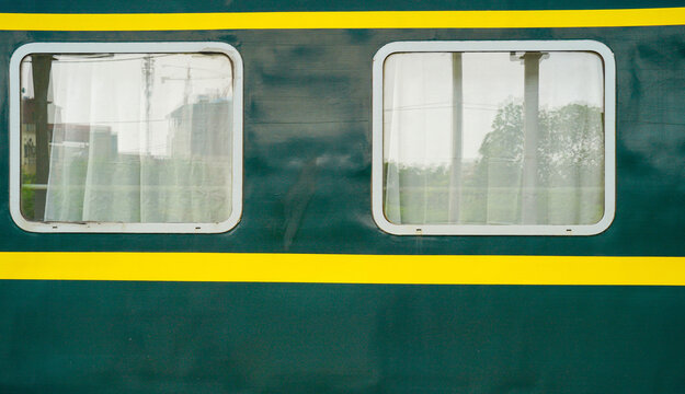 Train windows with sheer curtains, highlighting a serene, green exterior.