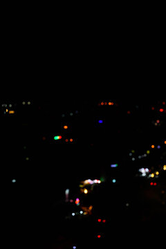 Vibrant city lights twinkle in the night, creating a blurred but colorful scene.