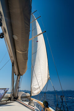 Mainsail on a sailing yacht while cruising across the sea under a clear blue sky. Concept of wind power, sailing, navigation, freedom and life aboard.