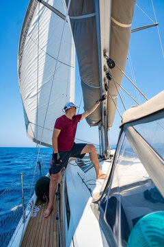Man monitoring the mainsail while sailing a yacht offshore. Seamanship and navigation skills during a long distance voyage.