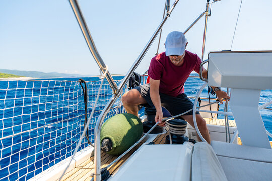 Experienced sailor trimming a sailing line on a modern yacht during an offshore passage. Seamanship, active boat handling, navigation skills and confident cruising under sail.