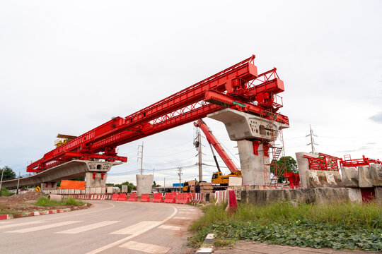 Massive red launching gantry installing elevated railway bridge segments at a construction site, showcasing modern infrastructure engineering, transportation development, and urban civil engineering.