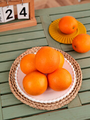 Fresh Gannan Blood Oranges in Wicker Basket on Green Wooden Table with Vintage Calendar © Nguyen
