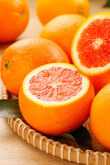 Fresh Blood Oranges and Red Grapefruit Halves in Wicker Basket on Wood Surface © TranThi