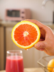 Fresh Blood Orange Slice in Hand - Vibrant Red Citrus Fruit in Modern Kitchen Setting © TranThi