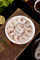 Fresh Raw Shrimp in Bowl on Wooden Board Ready for Cooking with Herbs and Lemon © TranThi