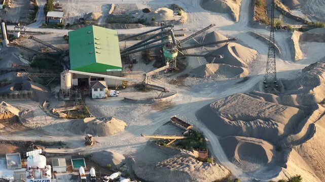 Aerial view of the Holcim concrete plant and quarry with gravel piles, conveyor belts, and cement trucks in Sausheim, Grand Est, France.