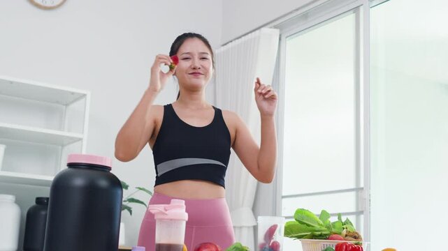 Healthy eating expert recording mobile video about fresh fruits and green veggies. Modern Asian woman in sportswear sharing wellness motivation and daily diet preparation.