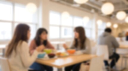 Obraz premium Blurred group of colleagues chatting during lunch break in modern bright office cafeteria with large windows and comfortable seating while enjoying meal and conversation together