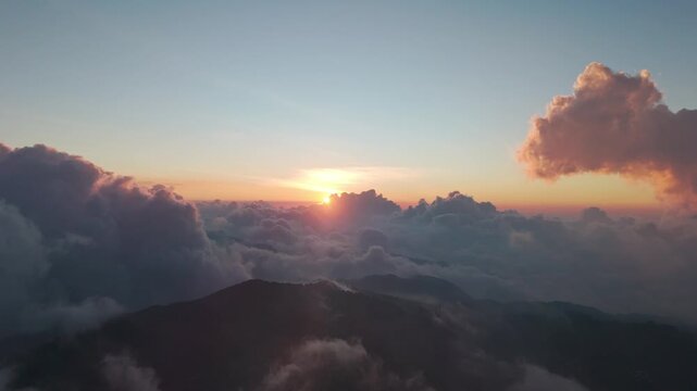 Aerial view of sunset over Telaga Dringo with dramatic cloud inversion and mountain peaks in Kecamatan Batur, Jawa Tengah, Indonesia.