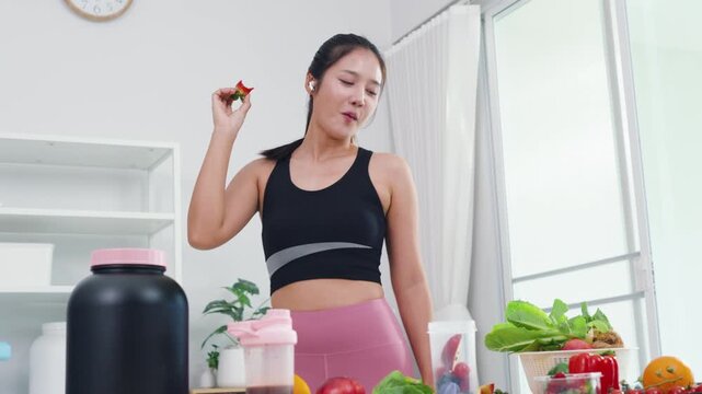 Healthy eating expert recording mobile video about fresh fruits and green veggies. Modern Asian woman in sportswear sharing wellness motivation and daily diet preparation.