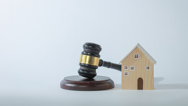 Serious gavel and wooden house model show real estate dispute concept for legal property judgment with stressful atmosphere background