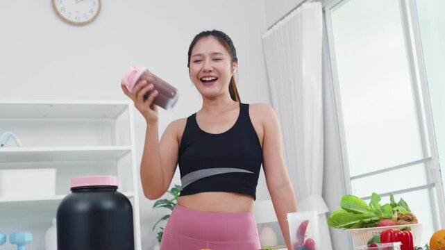 Healthy eating expert recording mobile video about fresh fruits and green veggies. Modern Asian woman in sportswear sharing wellness motivation and daily diet preparation.