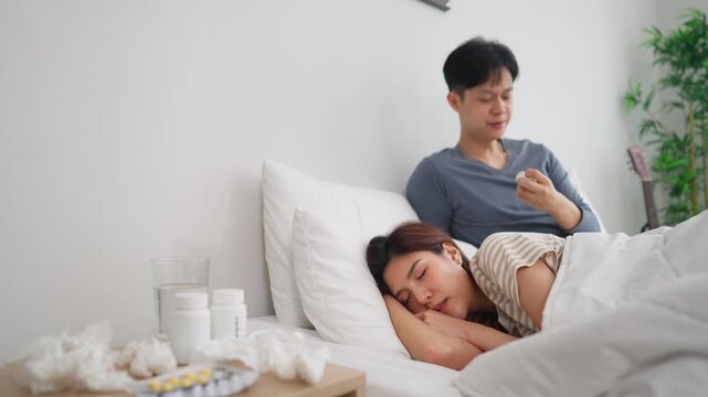 Asian young couple lying on bed in bedroom, looking sick and unwell. 