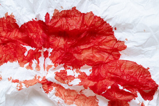 A white paper napkin with red blood stains on the theme of nosebleeds, wounds, injuries