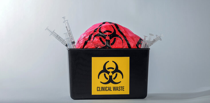 Medical biohazard container filled with hazardous red bag syringe needle presenting cautious mood for proper healthcare waste management