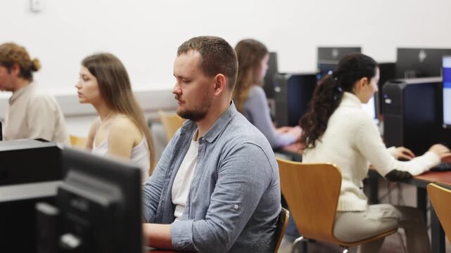 Man student of computer courses looks at monitor screen, types on keyboard and does work. High quality 4k footage