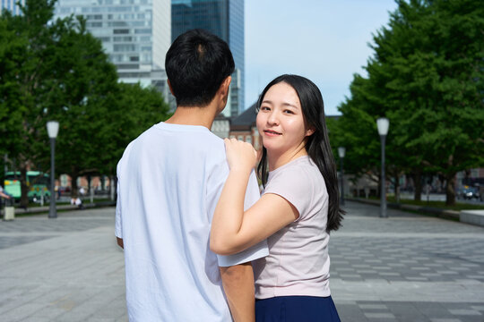 Young Japanese Man and Woman Standing Together on City Street, Gazing at Each Other