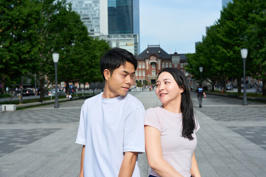 Young Japanese Man and Woman Standing Together on City Street, Gazing at Each Other
