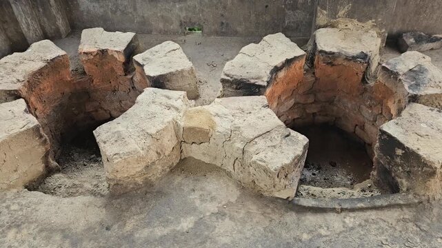 Close-up footage of a traditional double-mouth earthen and brick cooking stove, commonly known as a chulha, built at ground level for wood-fired cooking
