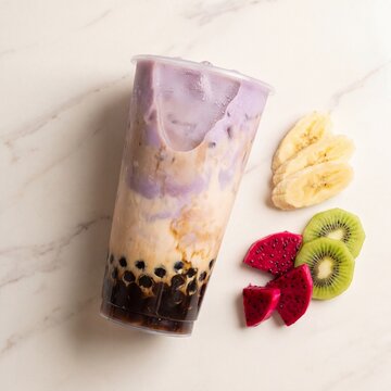 Layered boba tea and colorful tropical fruit arrangement on marble surface
